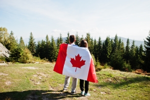 Happy Canada Day. Couple with large Canadian flag celebration in Знакомства в Торонто и Онтарио