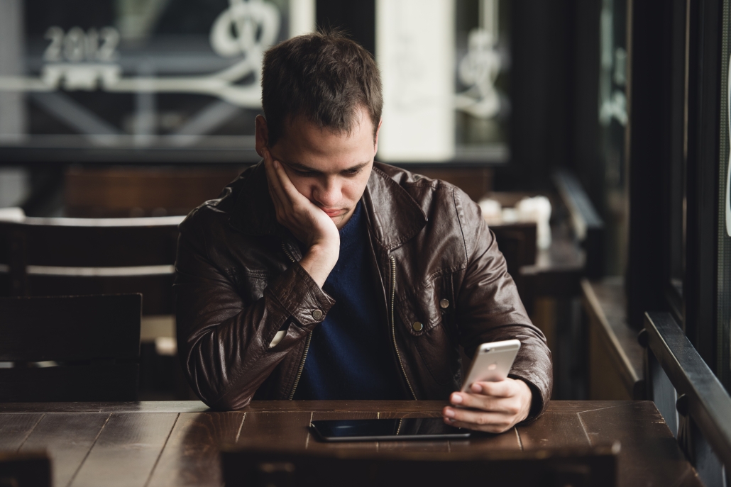 Closeup portrait, stressed young man in purple sweater, shocked surprised, horrified and disturbed, by what he sees on his cell phone, isolated indoors background. Торонто Знакомства