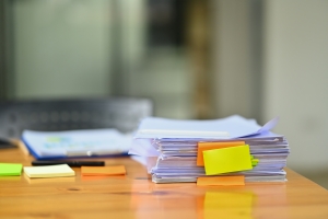 Pile of documents with colorful sticky notes on wooden office de