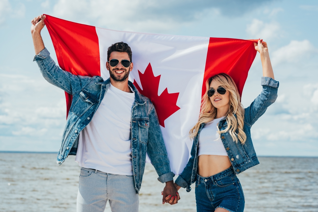 blonde woman and man in jacket holding canadian flag